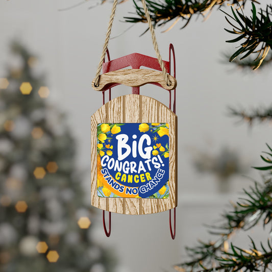 Victory Over Cancer Sled Ornament. Decorative sled ornament with 'Big Congrats! Cancer Stands No Chance' text, hanging from a tree.