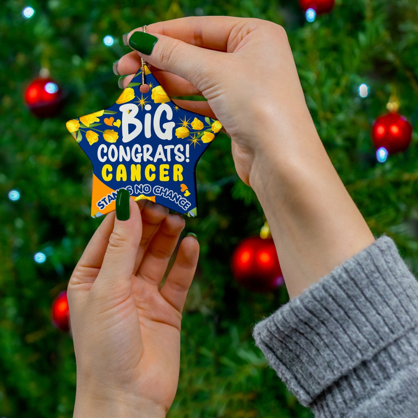 Cancer Motivational Ceramic Ornament of Victory. Hand holding a colorful ornament with 'Big Congrats! Cancer Stays No Chance' text against a Christmas tree background.
