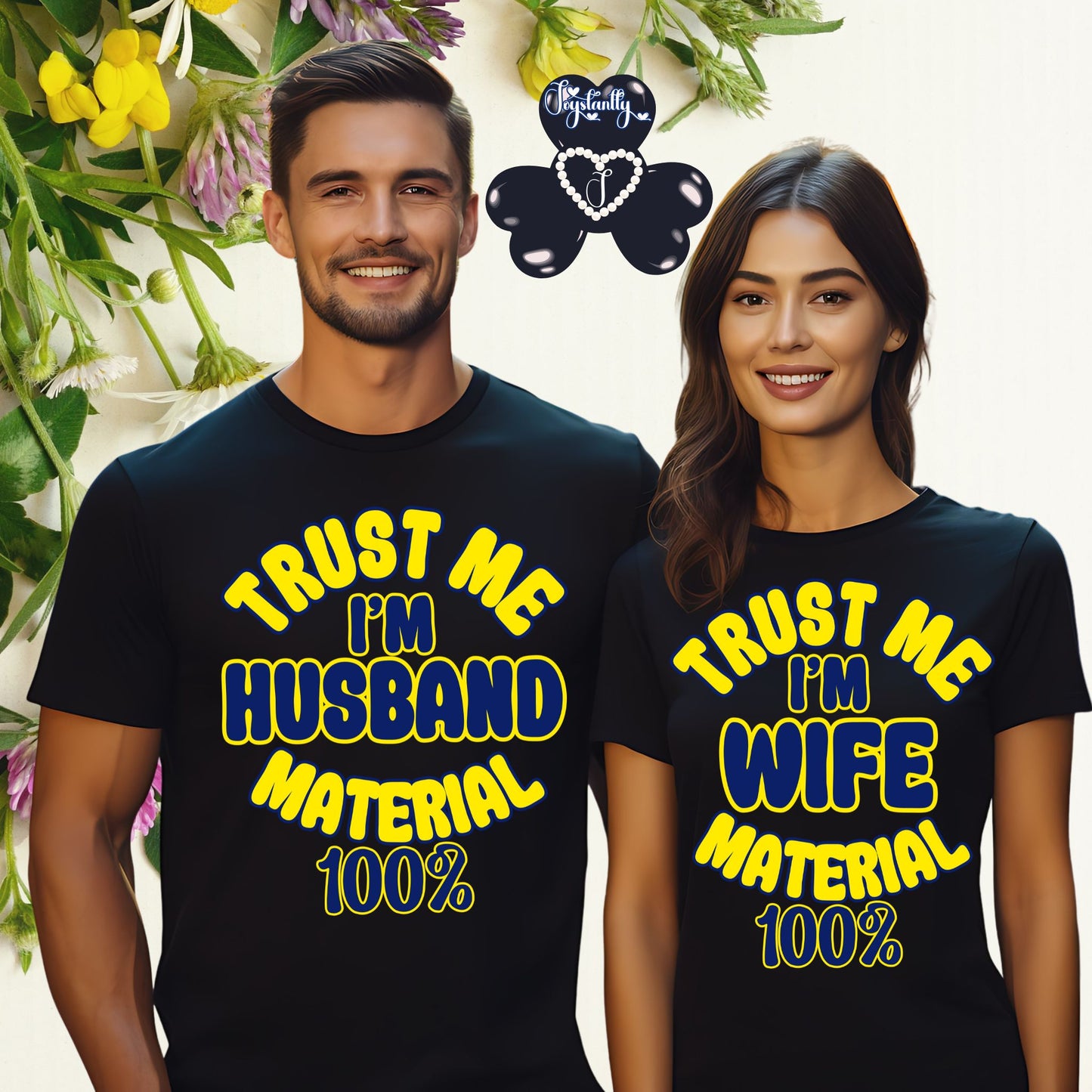 Two people wearing matching navy blue t-shirts with yellow text, standing in front of flowers.