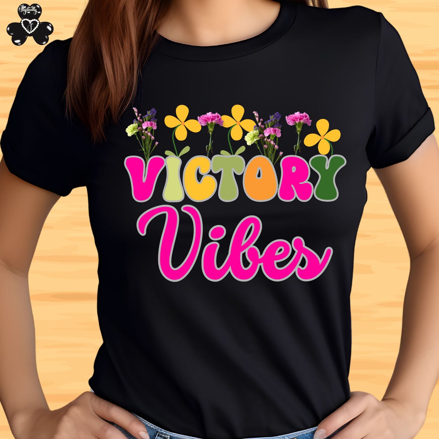 Motivational T-shirt for positive affirmations. Black t-shirt with 'Victory Vibes' and colorful flowers on a wooden surface