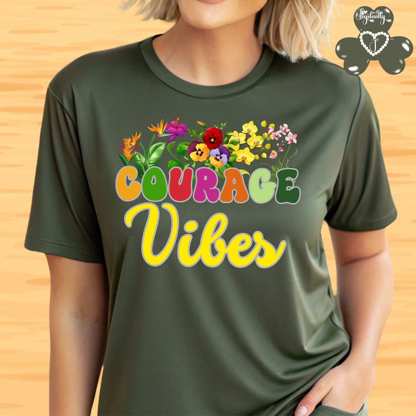 Motivational shirt. Person wearing a green t-shirt with 'Courage Vibes' and colorful flowers on a wooden background