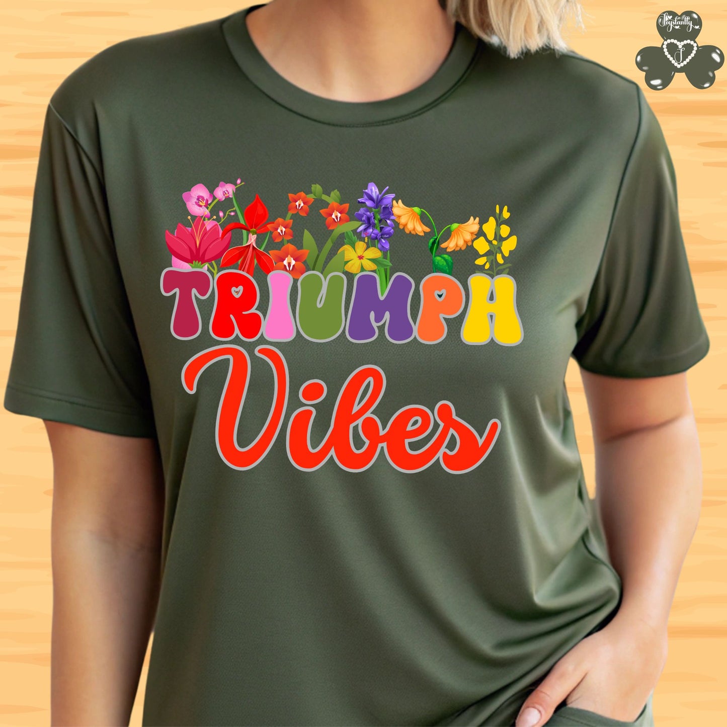 Motivational shirt. Green t-shirt with 'Triumph Vibes' text and colorful flowers on a wooden background