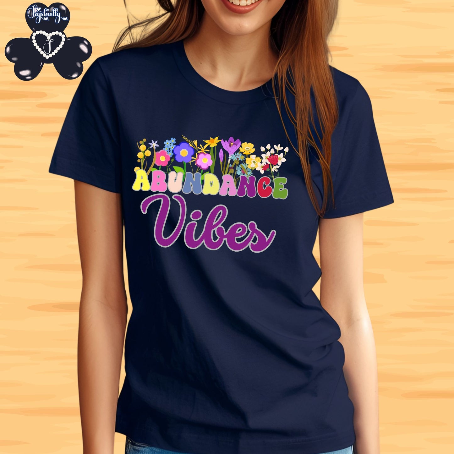 Positive Affirmation shirt. Navy blue t-shirt with 'Abundance Vibes' text and colorful flowers on a wooden background
