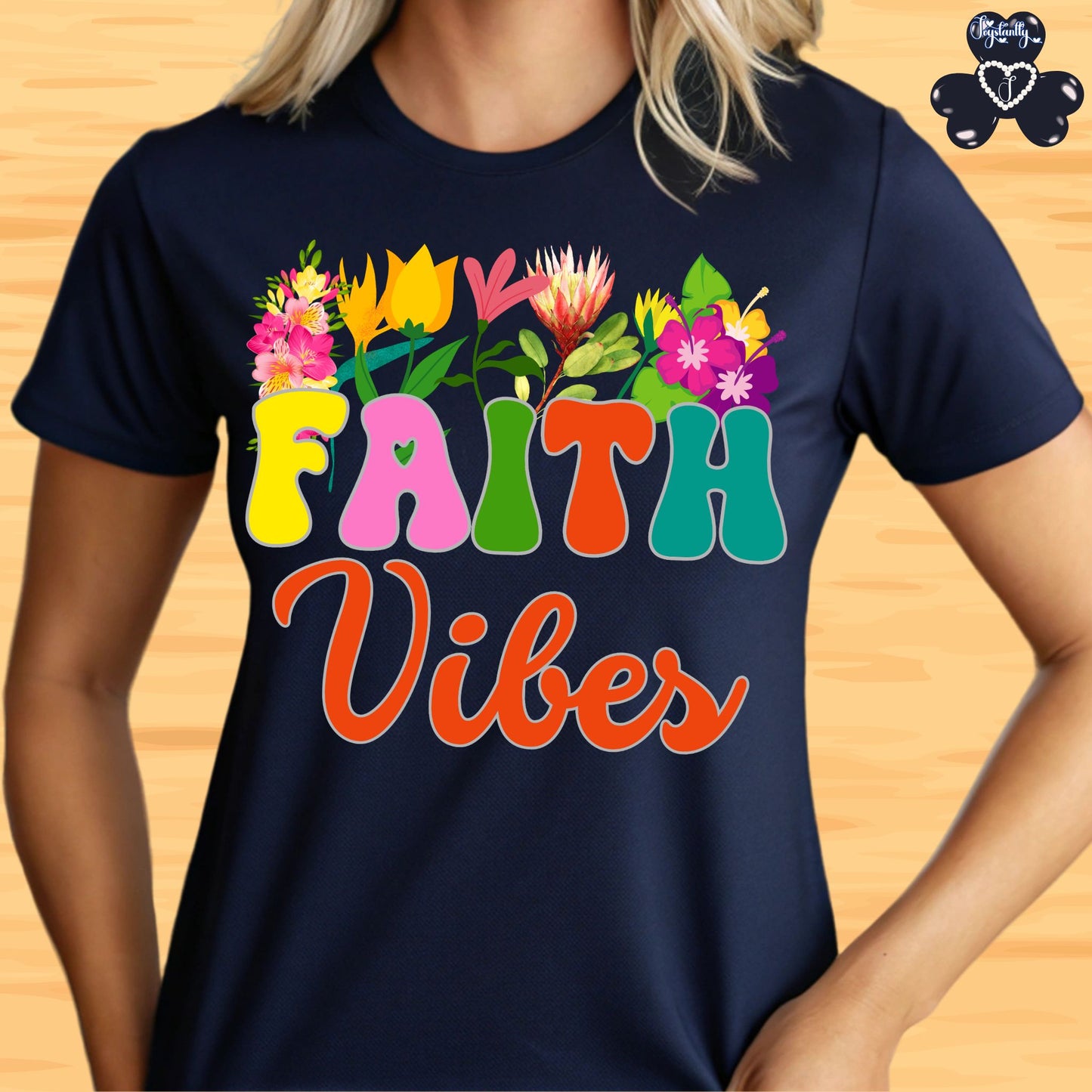 Motivational T-shirt for positive affirmations. Navy blue t-shirt with colorful 'Faith Vibes' design on a wooden surface