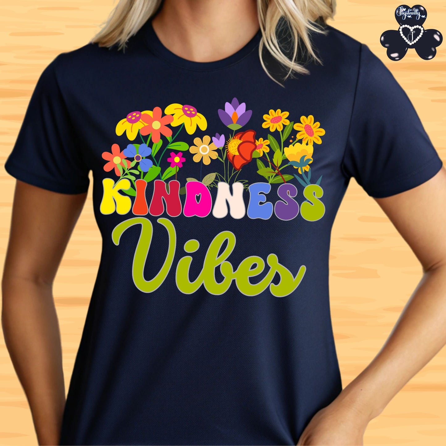 Motivational T-shirt for positive affirmations. Navy blue t-shirt with colorful flowers and 'Kindness Vibes' text on a wooden surface