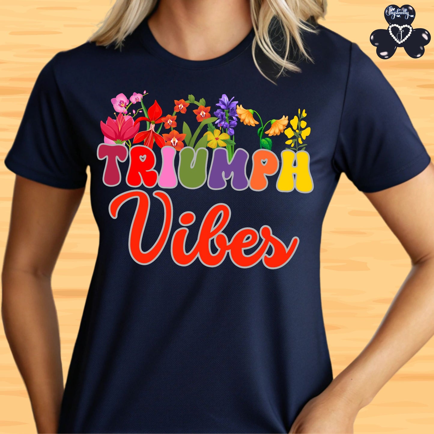 Motivational T-shirt for positive affirmations. Navy blue t-shirt with colorful 'Triumph Vibes' design on a wooden surface