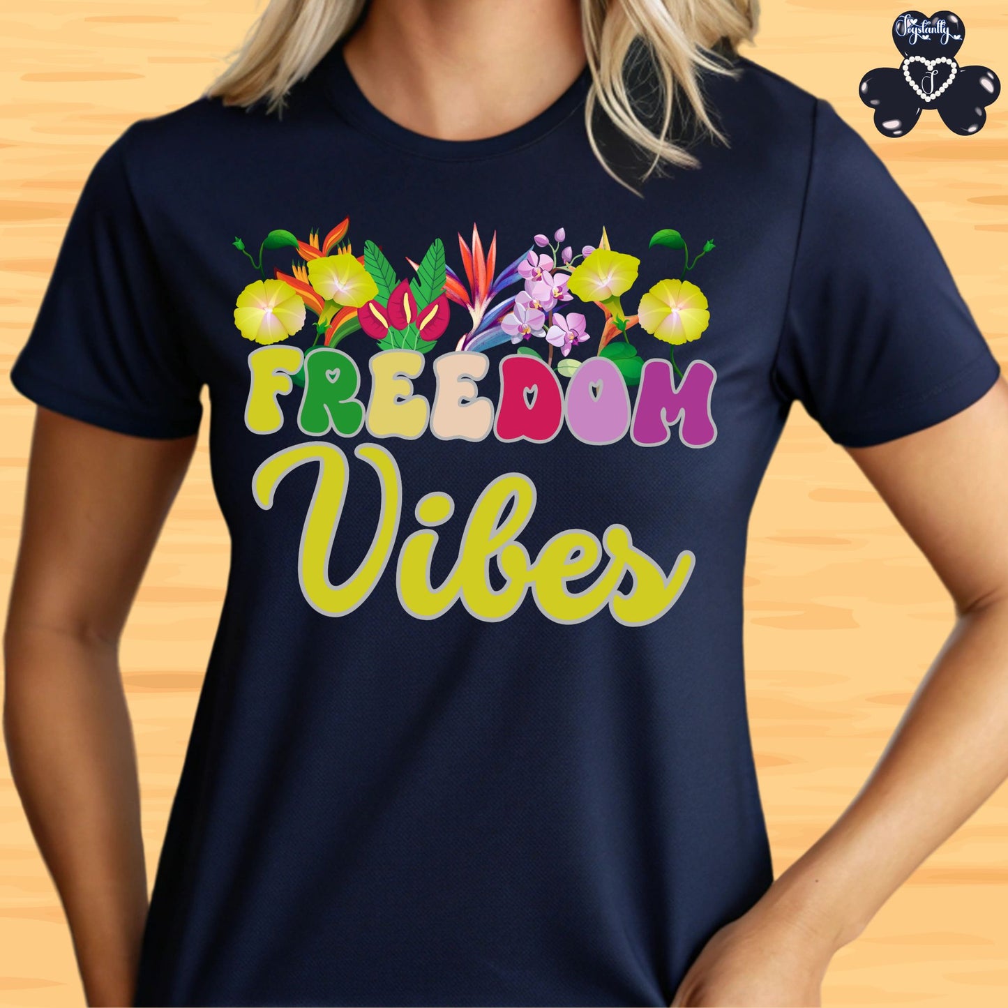 Motivational T-shirt for positive affirmations. Navy blue t-shirt with 'Freedom Vibes' text and floral graphics on a wooden surface