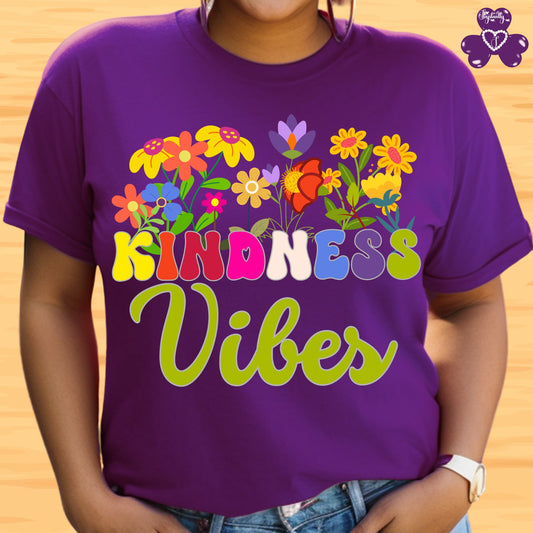 Motivational T-shirt for positive affirmations. Purple t-shirt with colorful flowers and 'Kindness Vibes' text on a wooden background
