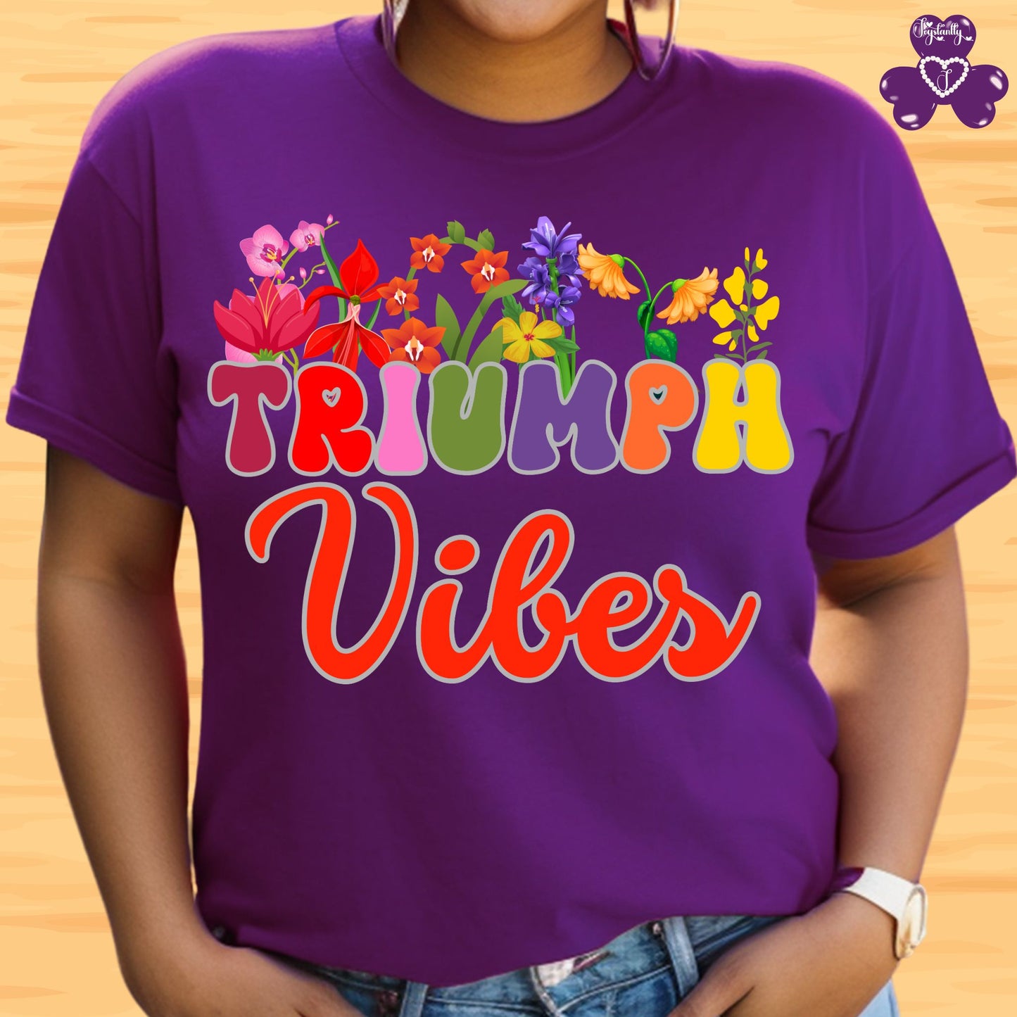 Motivational T-shirt for positive affirmations. Purple t-shirt with colorful floral design and 'TRIUMPH Vibes' text on a wooden background