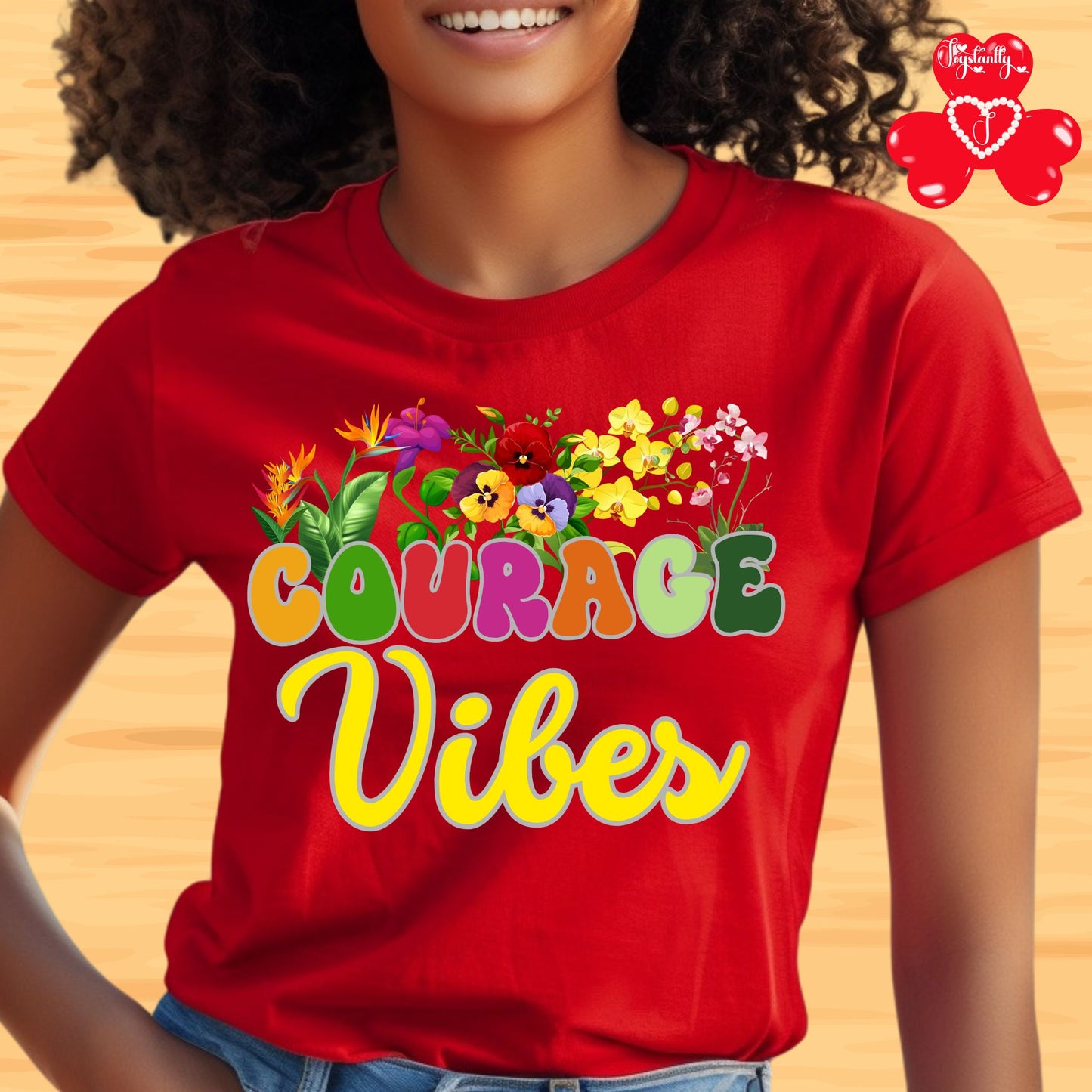 Motivational shirt. Person wearing a red t-shirt with 'Courage Vibes' and colorful flowers on a wooden background