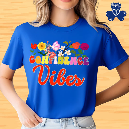 Motivational shirt. Person wearing a blue t-shirt with 'Confidence Vibes' text and colorful flowers on a wooden background