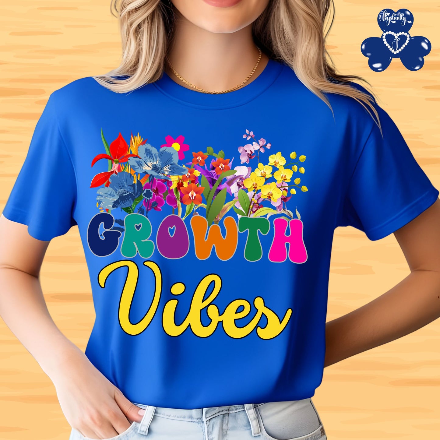 Motivational T-shirt for positive affirmations. Person wearing a blue t-shirt with colorful flowers and 'Growth Vibes' text on a wooden background