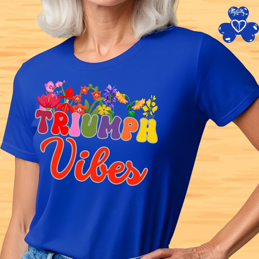Motivational shirt. Person wearing a blue t-shirt with 'Triumph Vibes' design on a wooden surface