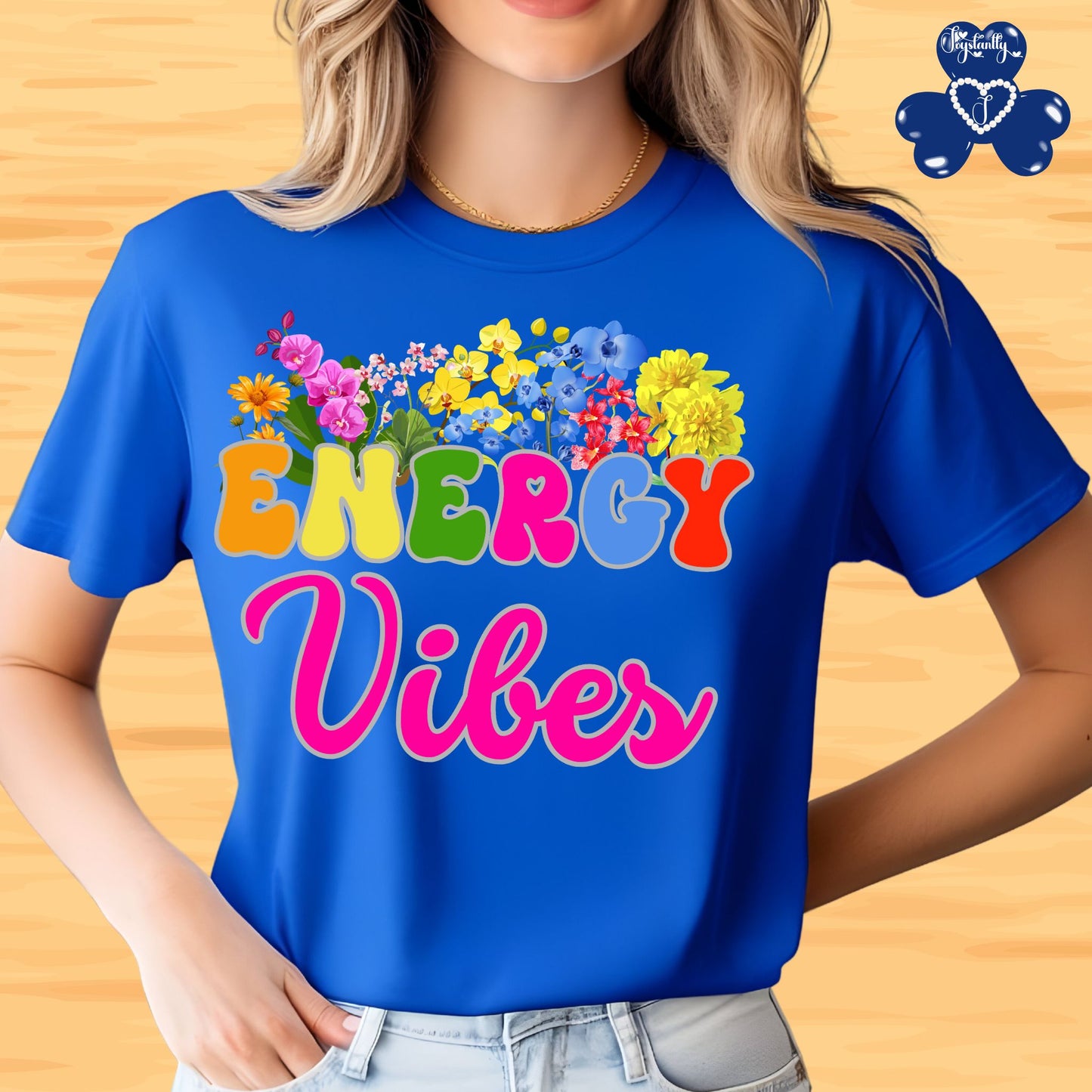 Motivational Shirts for Positive Affirmations. Person wearing a blue t-shirt with colorful text 'ENERGY Vibes' and floral design on a wooden background.