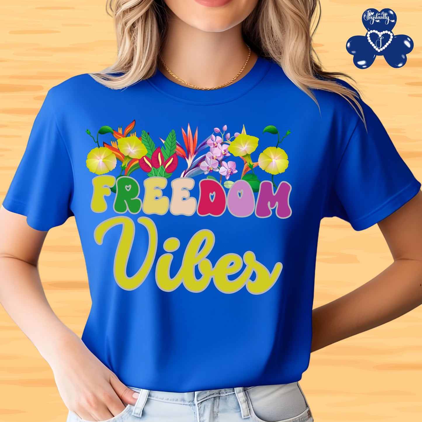 Motivational T-shirt for positive affirmations. Person wearing a blue t-shirt with 'Freedom Vibes' and floral designs on a wooden background