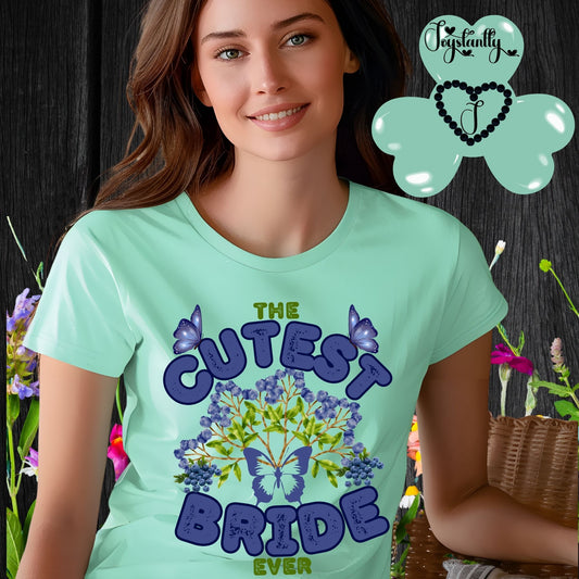 Woman wearing a mint green t-shirt with 'The Cutest Bride Ever' text and butterfly design, standing against a floral background.