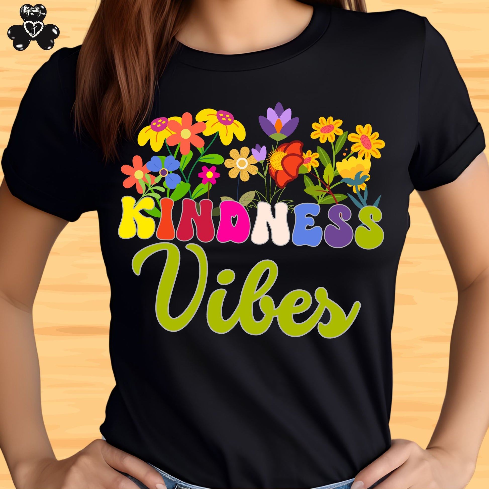 Motivational T-shirt for positive affirmations. Black t-shirt with colorful floral design and 'Kindness Vibes' text on a wooden surface.