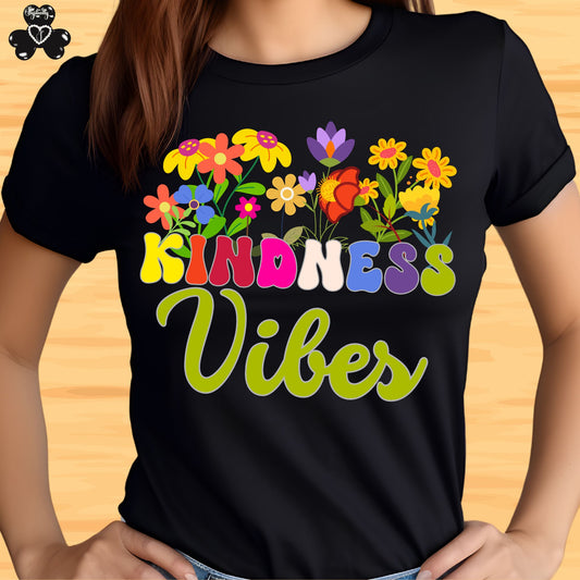 Motivational T-shirt for positive affirmations. Black t-shirt with colorful floral design and 'Kindness Vibes' text on a wooden surface.