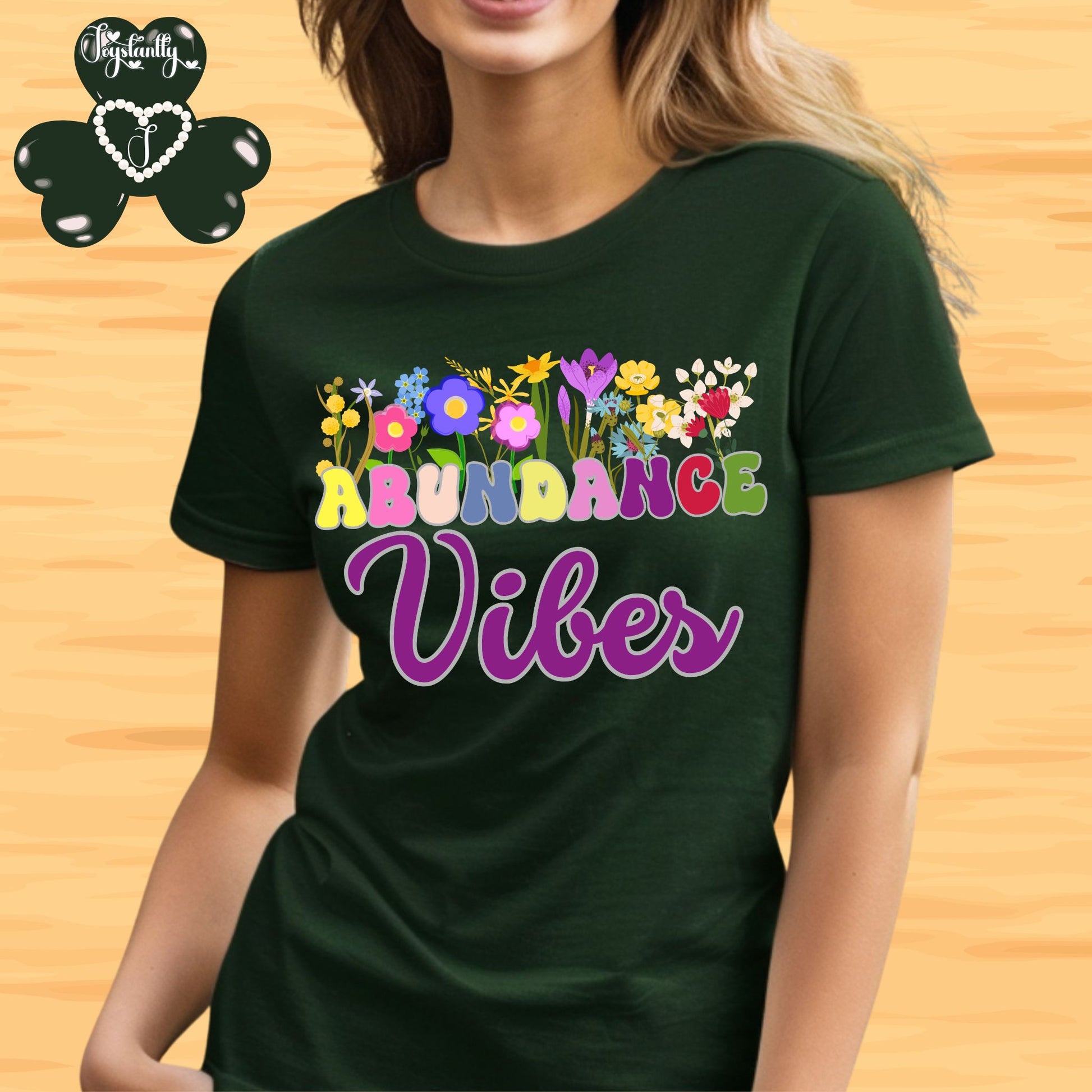 Positive Affirmation shirt. Person wearing a green t-shirt with 'Abundance Vibes' design on a wooden background