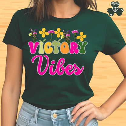 Motivational T-shirt for positive affirmations. Green t-shirt with 'Victory Vibes' text and flowers on a wooden surface