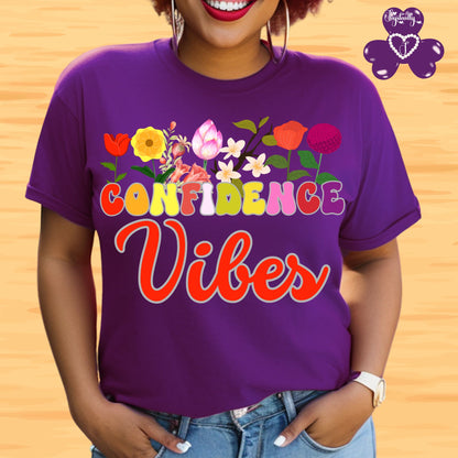 Positive affirmation shirt. Person wearing a purple t-shirt with colorful floral design and 'CONFIDENCE Vibes' text on a wooden background.