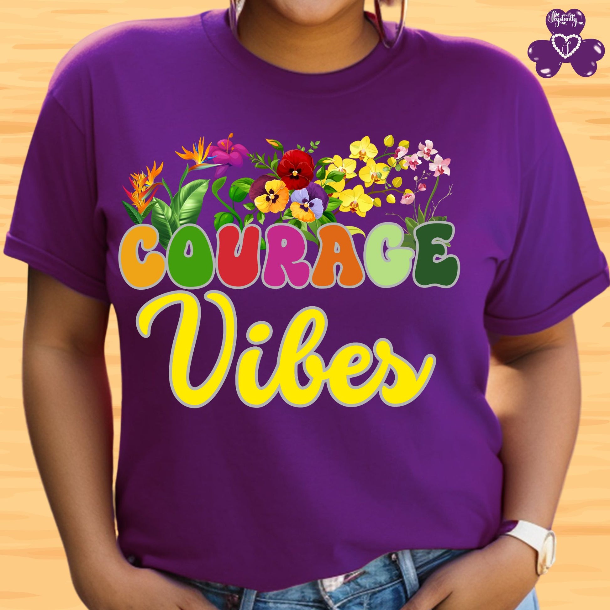 Positive affirmation shirt. Purple t-shirt with colorful 'Courage Vibes' design on a wooden background